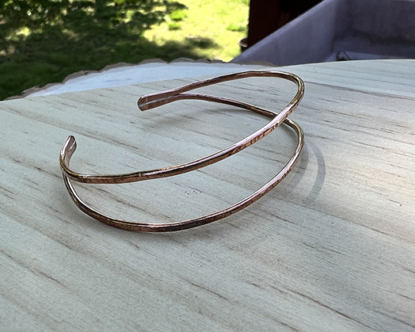 Thin copper wire shaped into a cuff bracelet.