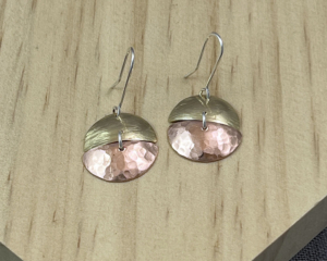 Earrings with textured brass top and copper bottom, attached with a sterling silver jump ring