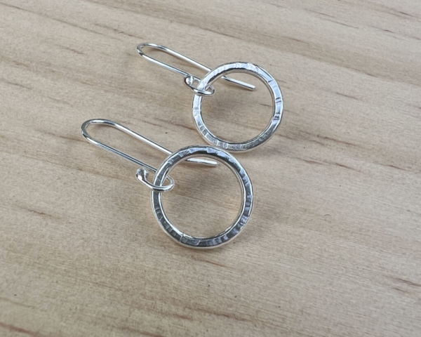 Small sterling silver circles with a hammered finish with handmade ear wires attached.