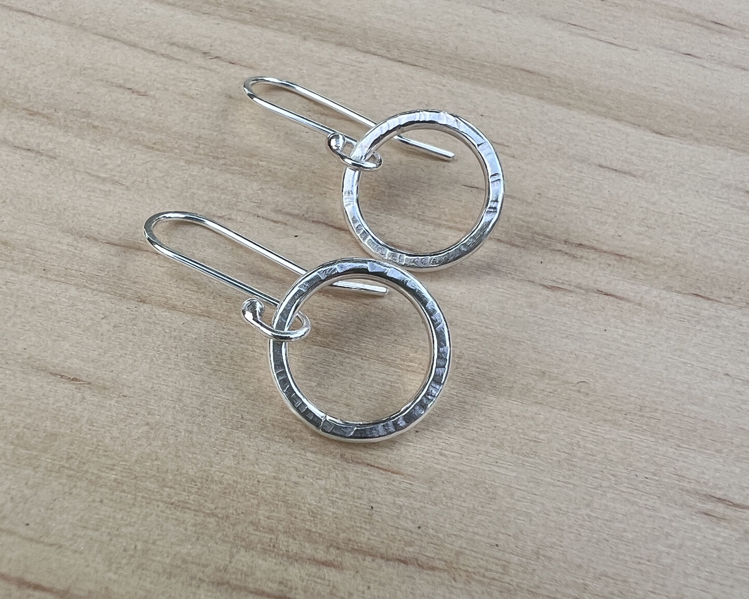 Small sterling silver circles with a hammered finish with handmade ear wires attached.