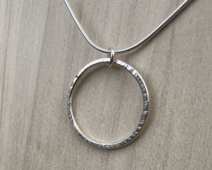 Thin wire shaped into a circle with a hammered finish. Sterling silver snake chain attached.