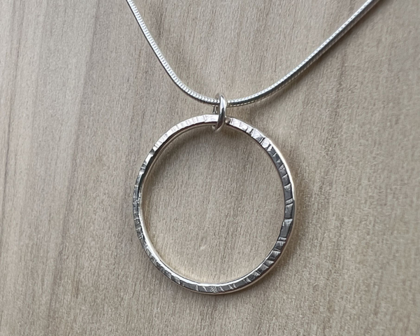 Thin wire shaped into a circle with a hammered finish. Sterling silver snake chain attached.